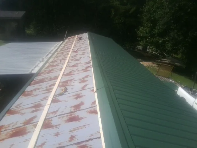 Old rusted panels beside newly installed green metal roofing — Wind Damage Roof Repair by Roofing Brothers in Scottsbluff