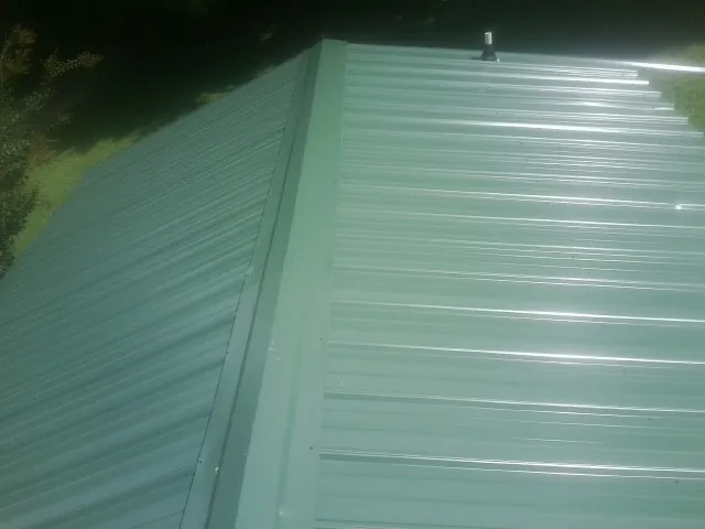 New green metal panels meeting at the ridge of a roof — Flat Roof Repair work by our crew in Scottsbluff