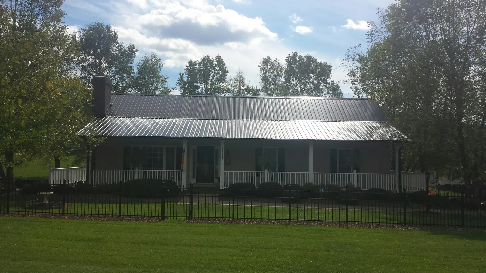 Gray metal roof on a brick ranch with a full width front porch — Gutter Guard Installation work by our crew in Scottsbluff