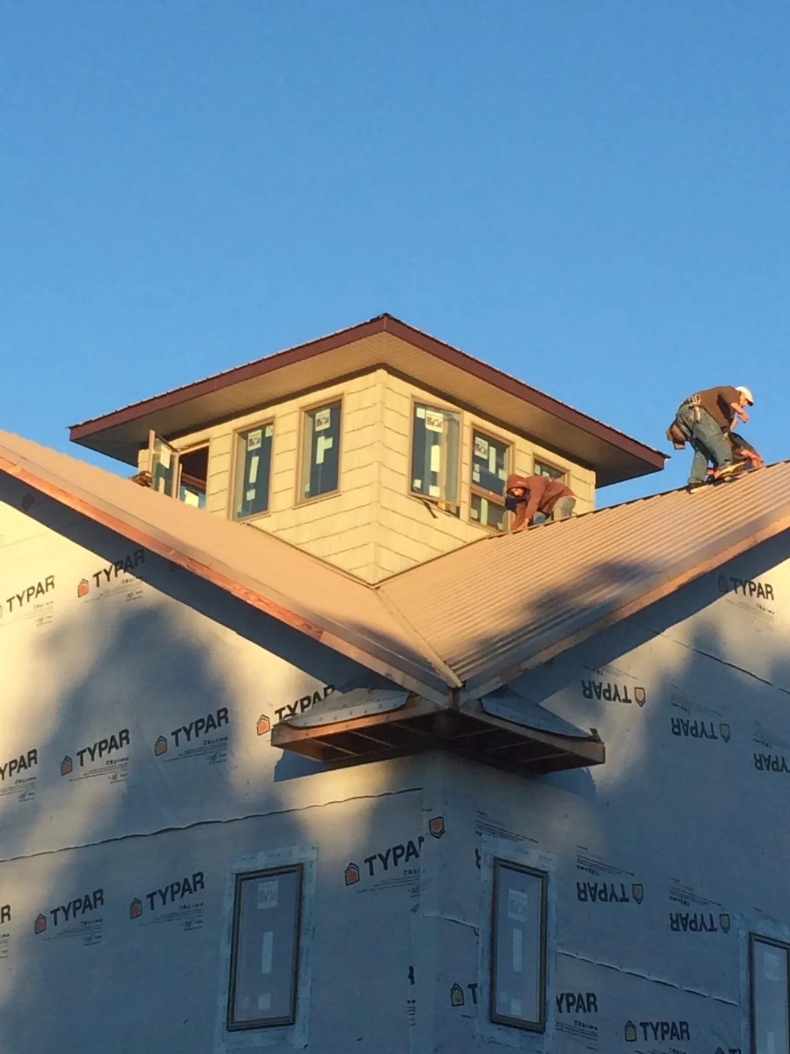 Roofers working around a rooftop cupola on a new metal roof at sunset — Roof Waterproofing in Scottsbluff by Roofing Brothers